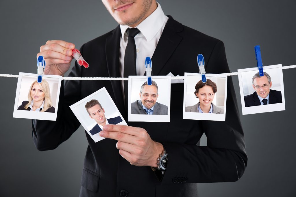 Midsection of businessman selecting candidate from clothesline against gray background